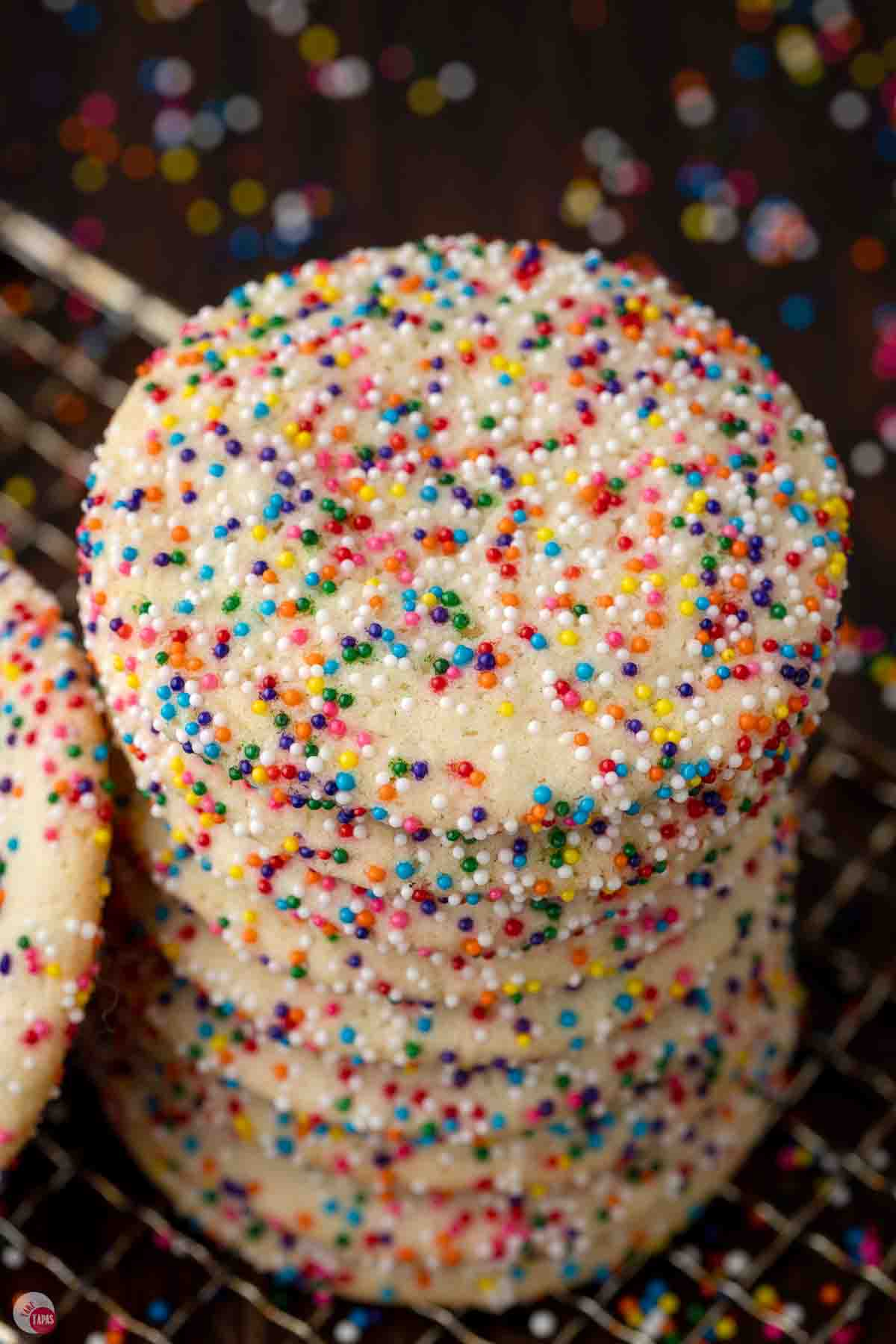 sprinkle cookies stacked on a wire cooling rack