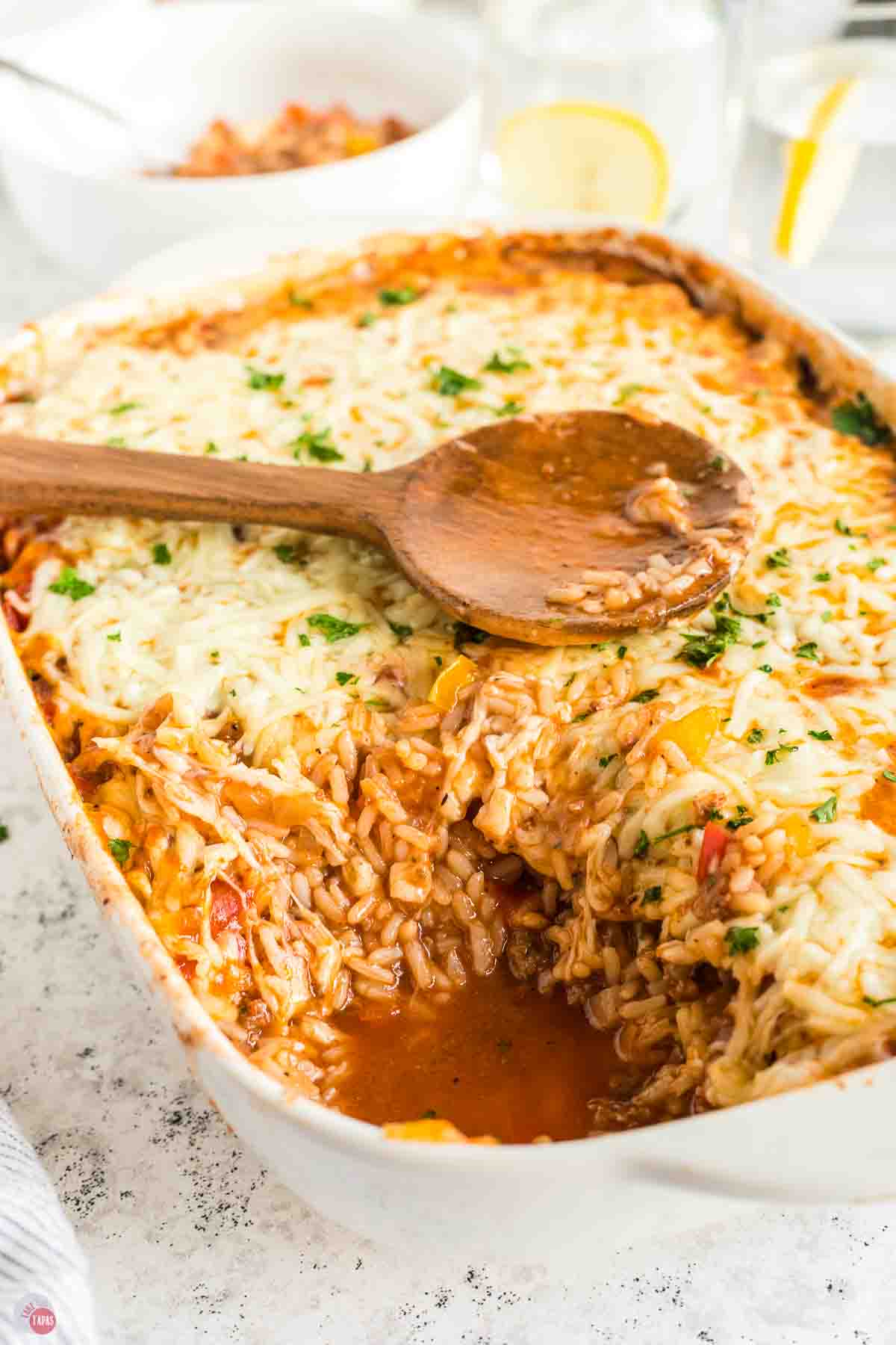side view of a casserole with ground beef, rice, and peppers with a scoop missing